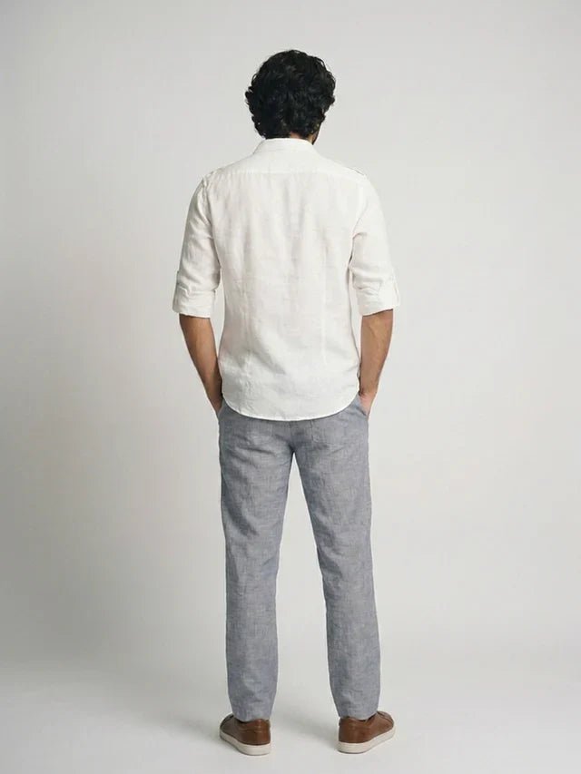 Person wearing a white shirt and gray pants on a plain background