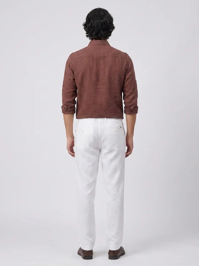 Man wearing a brown shirt and white pants on a white background