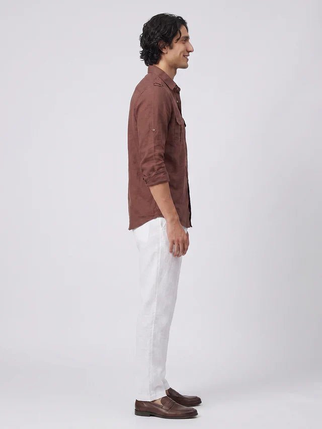 Man wearing a brown shirt and white pants on a white background