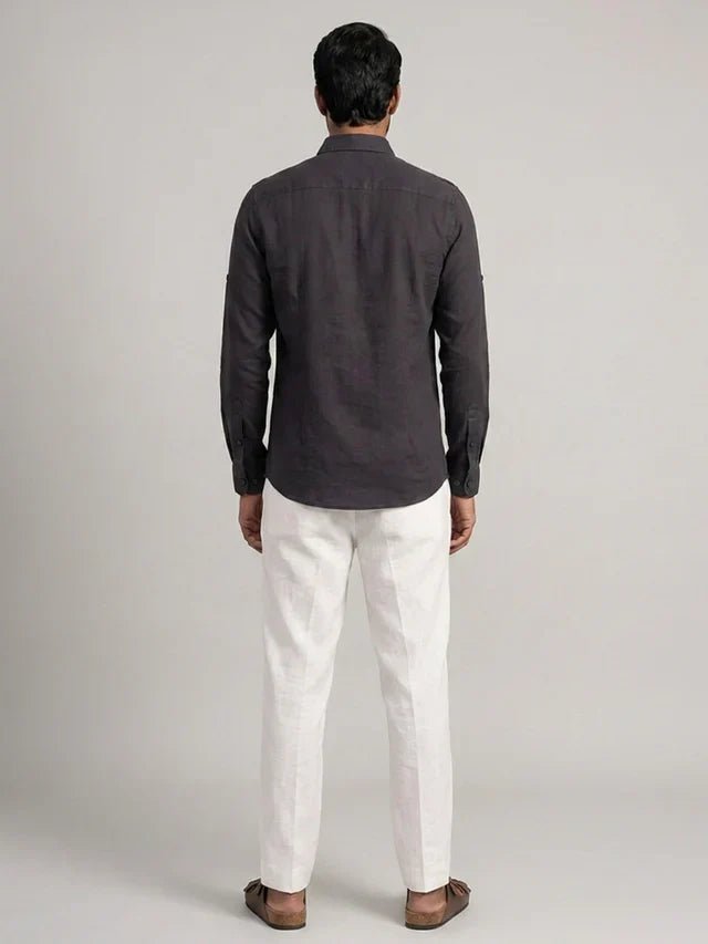 Man wearing a dark gray shirt and white pants on a light gray background