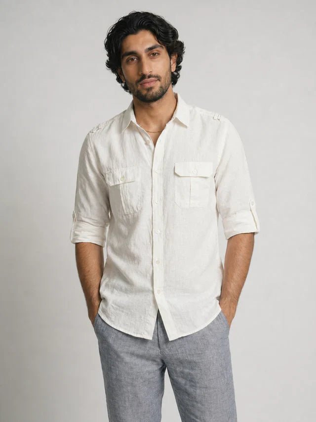 Man wearing a light-colored shirt and gray pants against a plain background