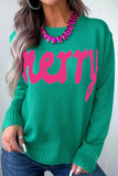 Woman wearing bright green “Merry” knit sweater with blue jeans.