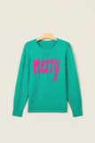 Teal green crewneck sweater with “merry” in bright pink script, hanging on a wooden hanger.