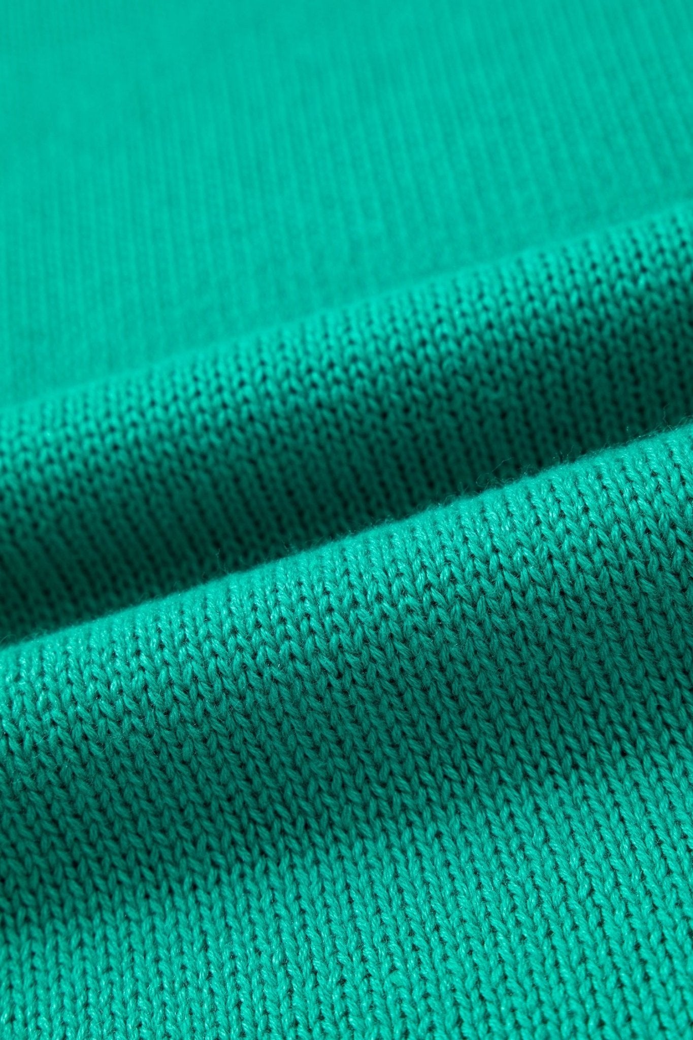 A close-up of a vibrant teal green ribbed knit fabric, showing the detailed texture and soft folds.