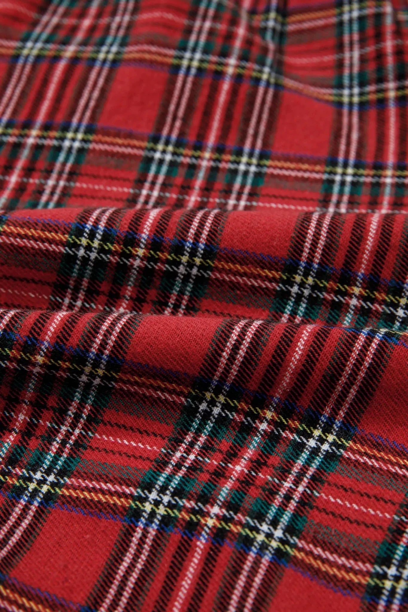 Close-up of red tartan plaid fabric with black, green, white, and yellow stripes