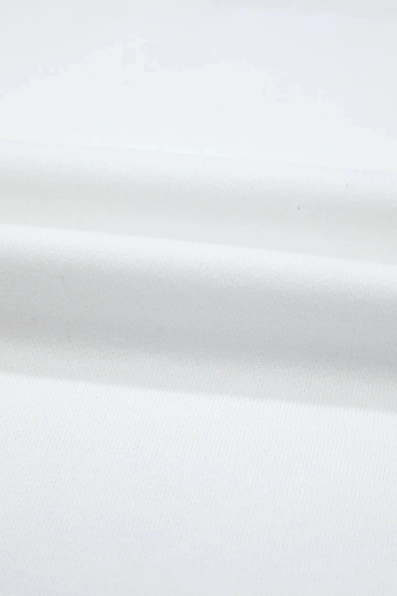 A close-up of white fabric with soft folds and a smooth texture.
