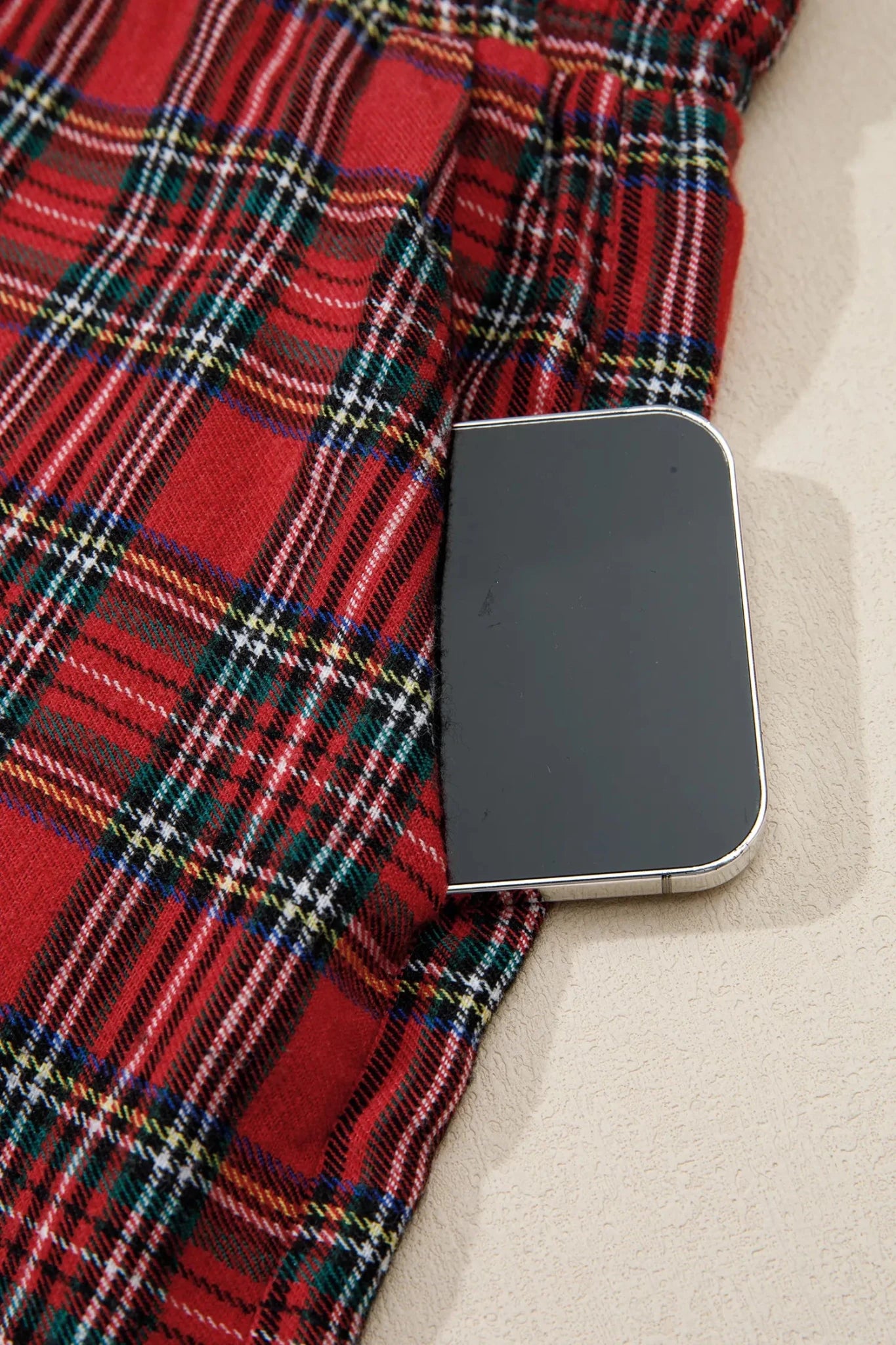 Close-up of red tartan plaid fabric with a black smartphone.