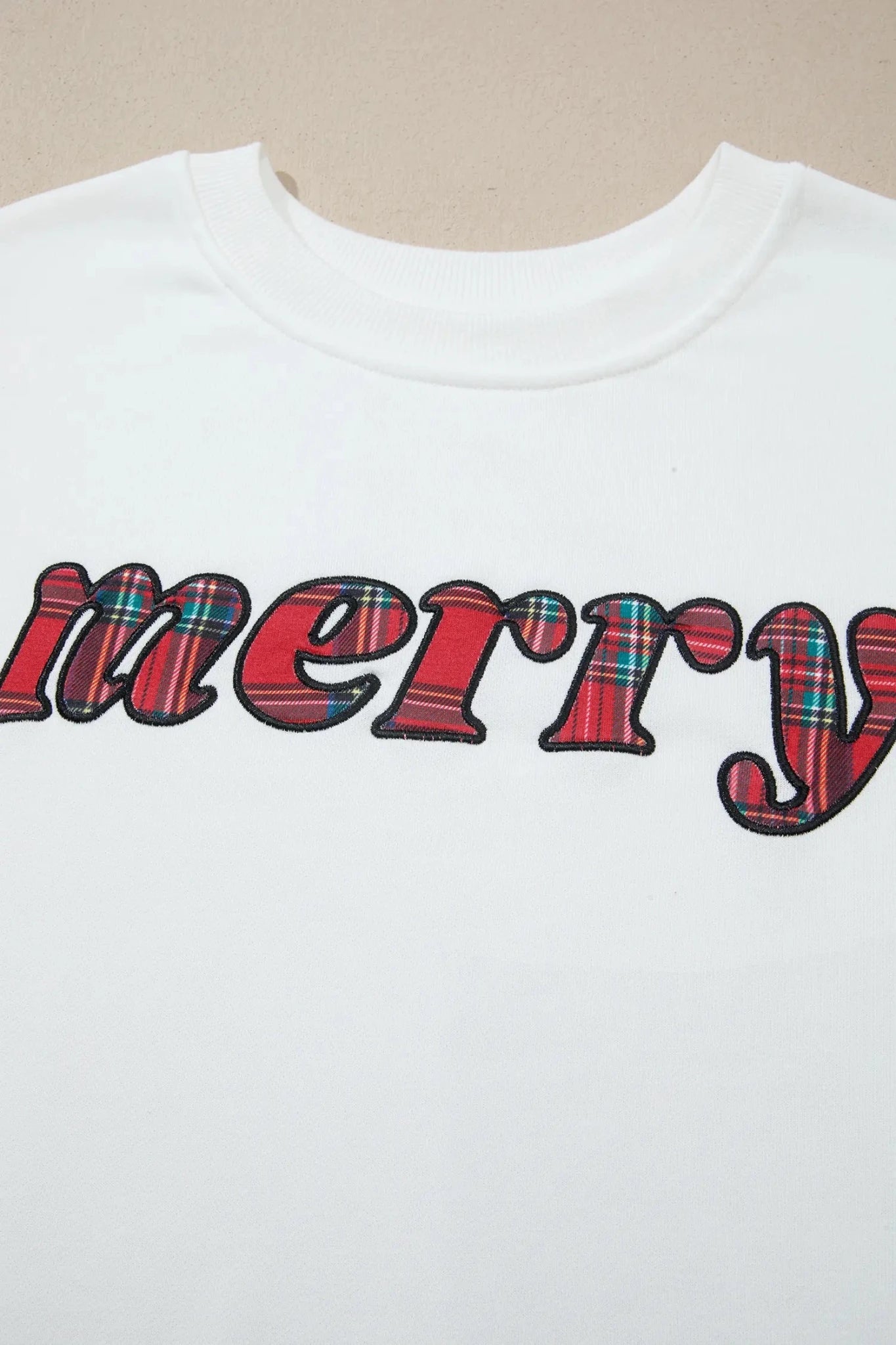 White crewneck sweatshirt with MERRY plaid graphic and black outline.