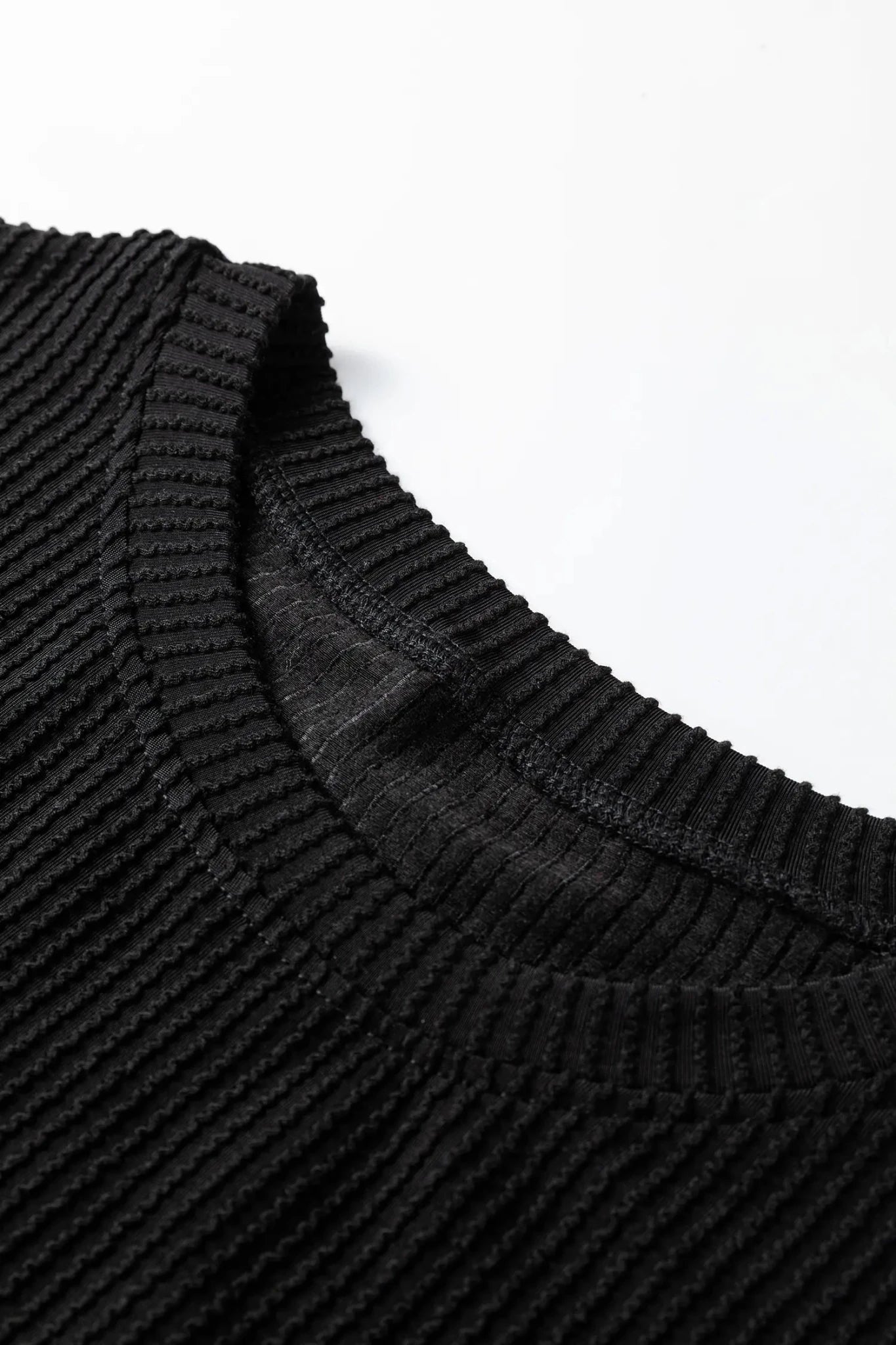 Close-up of a black ribbed sweater collar on a white background