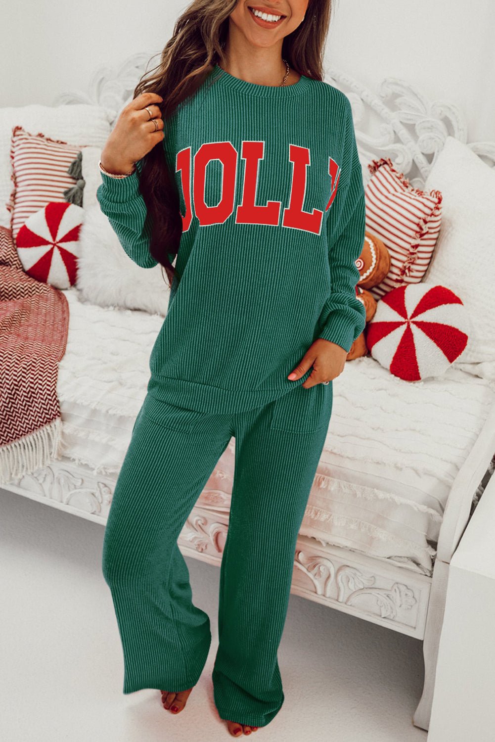 Person wearing a green outfit with 'HOLLY' text, sitting on a couch with festive pillows.