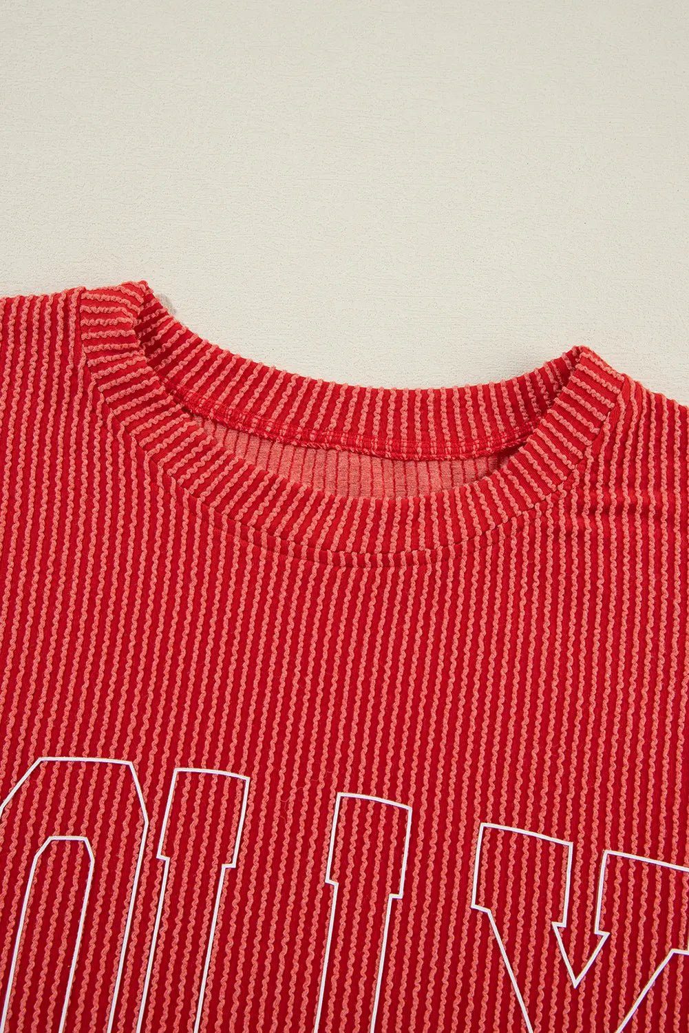 Red ribbed knit top with white outlined lettering across the chest.