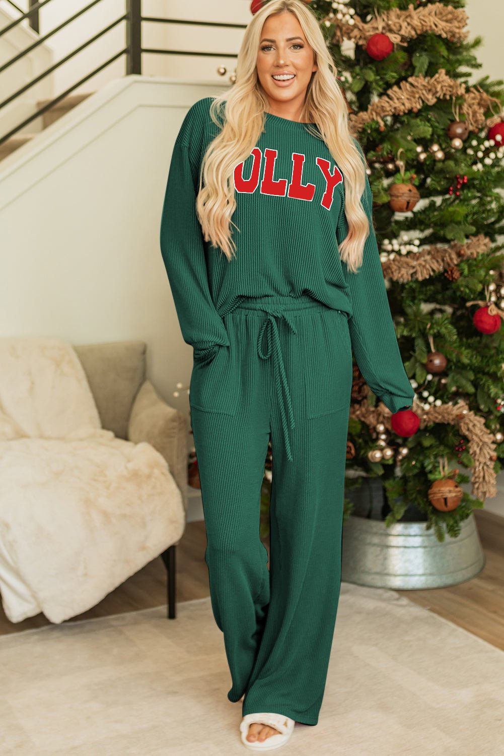 Woman wearing a green outfit with 'Molly' text in a festive indoor setting with a Christmas tree.