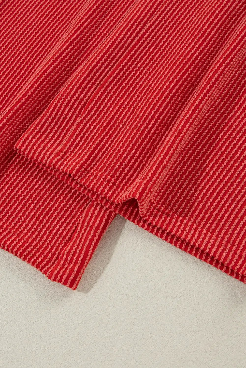 Close-up of red fabric with a textured pattern on a beige background