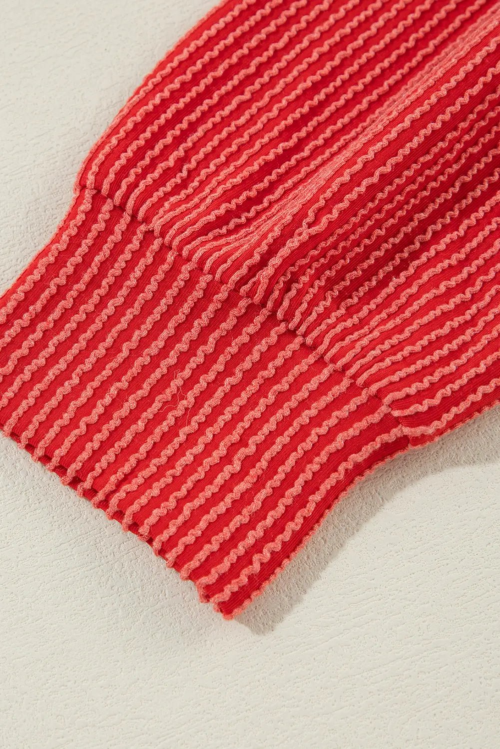 Red and white striped ribbed knit cuff with detailed fabric texture.