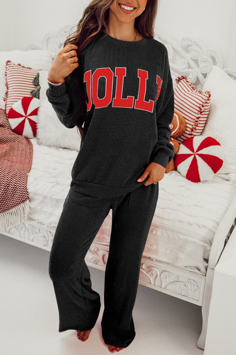 Person wearing a black sweater with 'HOLL' text in red, sitting on a couch with decorative pillows.