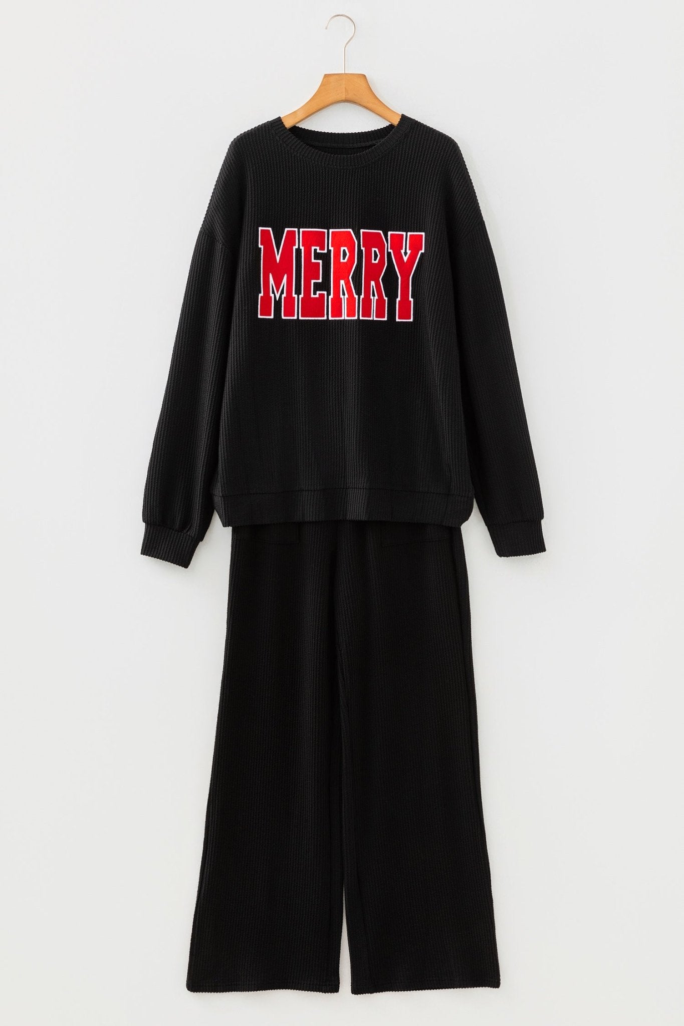 Black outfit with 'MERRY' text on a hanger against a white background