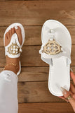 White sandals with gold embellishments on a wooden floor