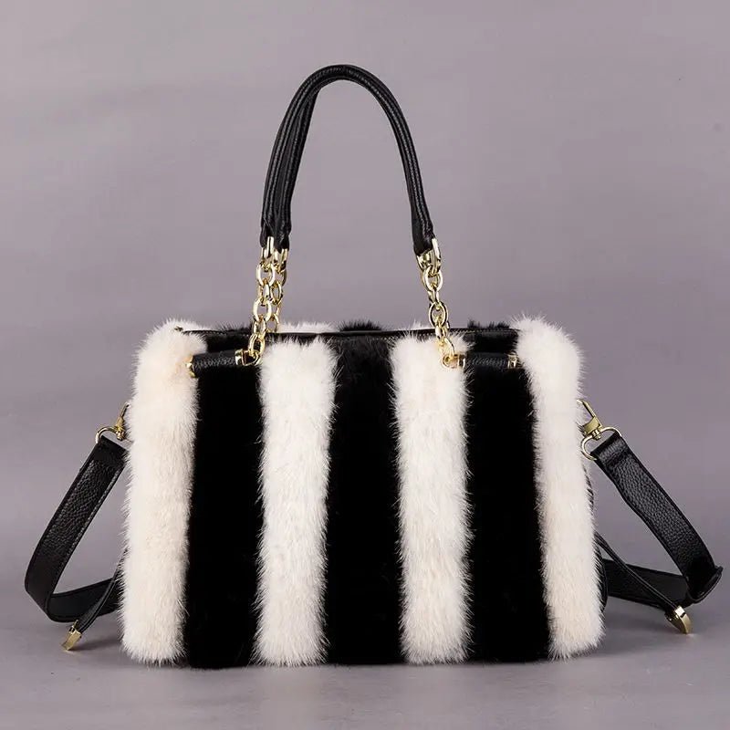 Black and white striped handbag with fur trim on a gray background