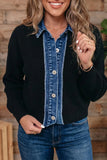 Woman in black ribbed cardigan over a blue denim shirt, paired with blue jeans against a rustic wooden wall.