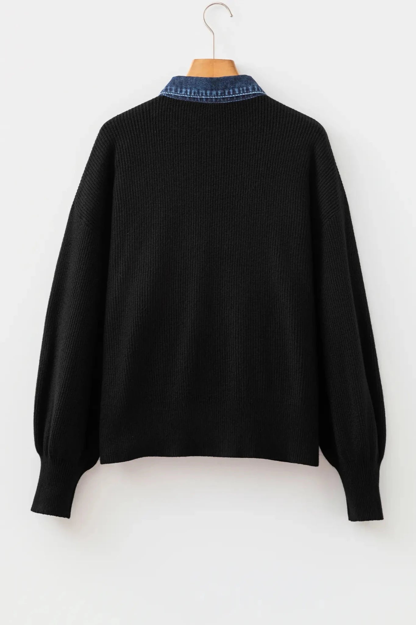 Black ribbed knit sweater with balloon sleeves and contrasting blue collar featuring white lettering.
