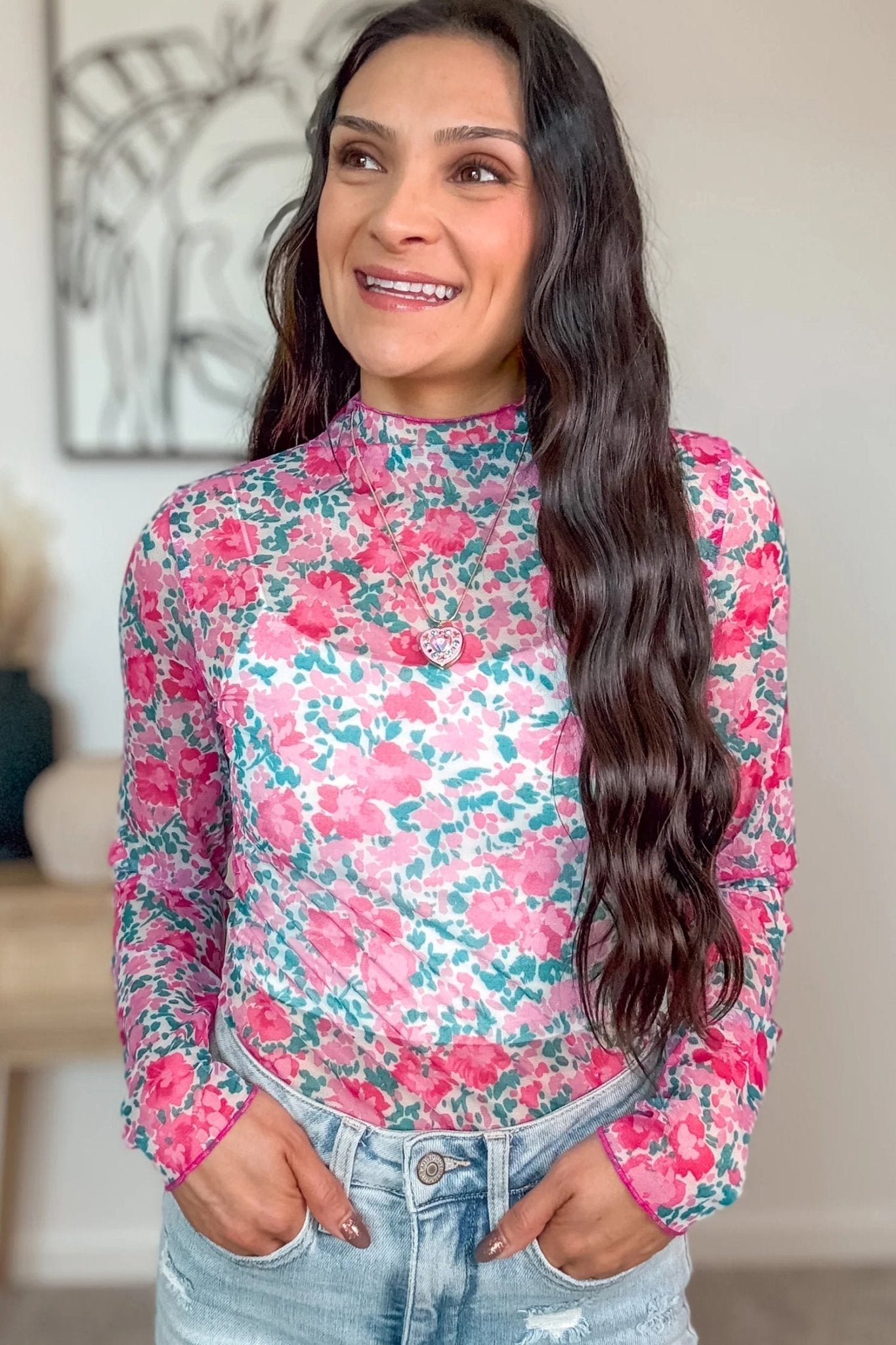 Woman wearing a floral long-sleeve top with a blurred indoor background