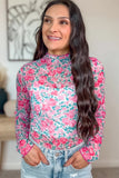 Woman wearing a floral long-sleeve top with a blurred indoor background