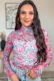 Woman wearing a floral long-sleeve top with a blurred indoor background