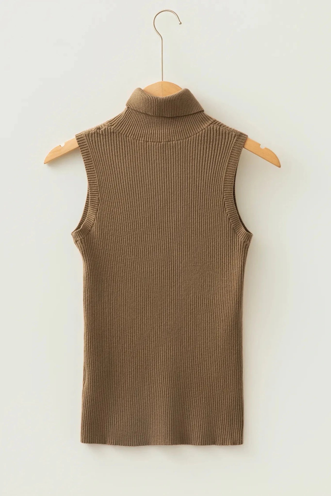 Sleeveless taupe-brown ribbed knit mock-neck top hanging on a wooden hanger against an off-white wall.