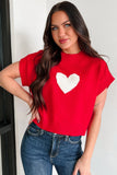 Woman wearing a red sweater with a white heart design against a white background