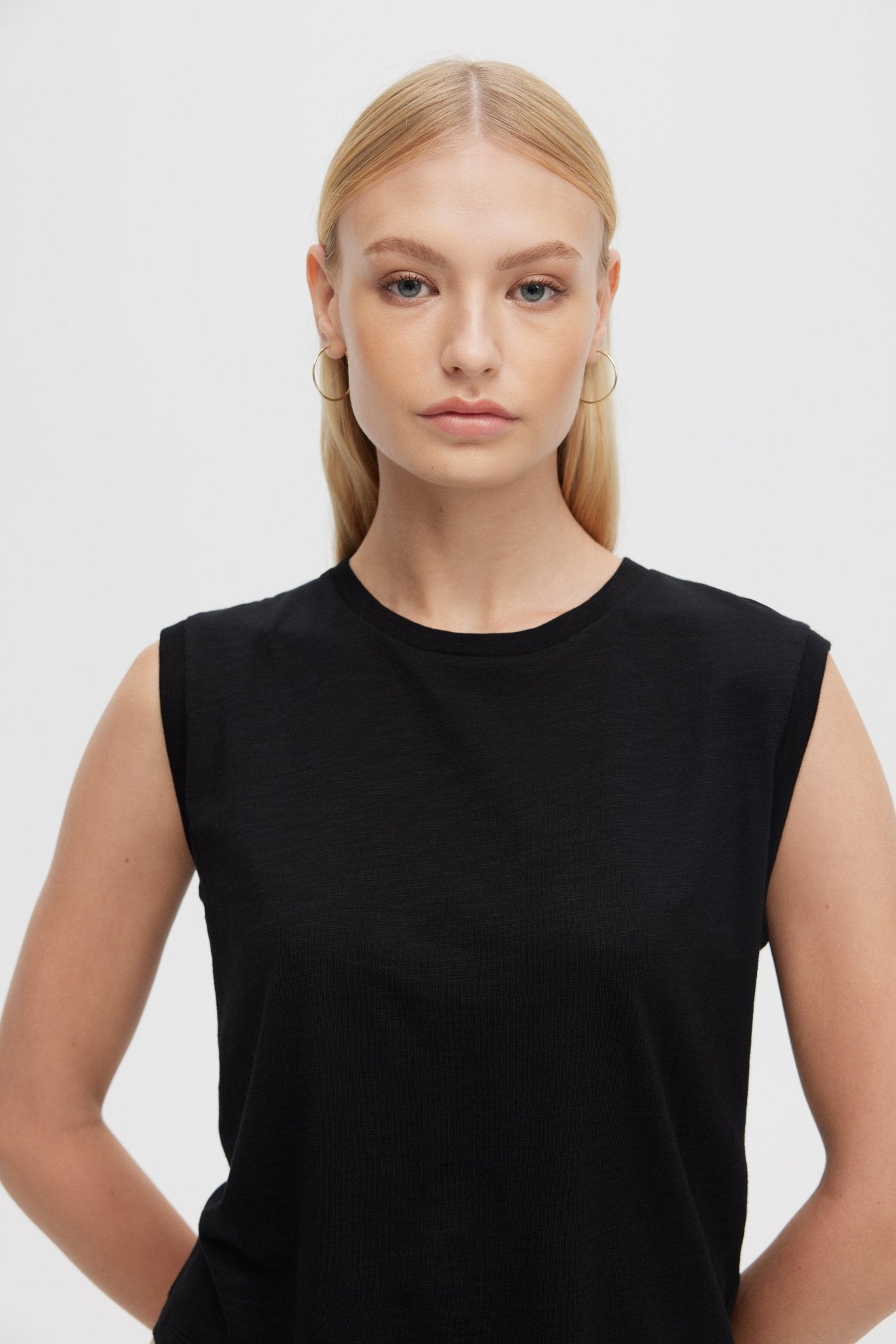 Woman wearing a black sleeveless top against a plain background