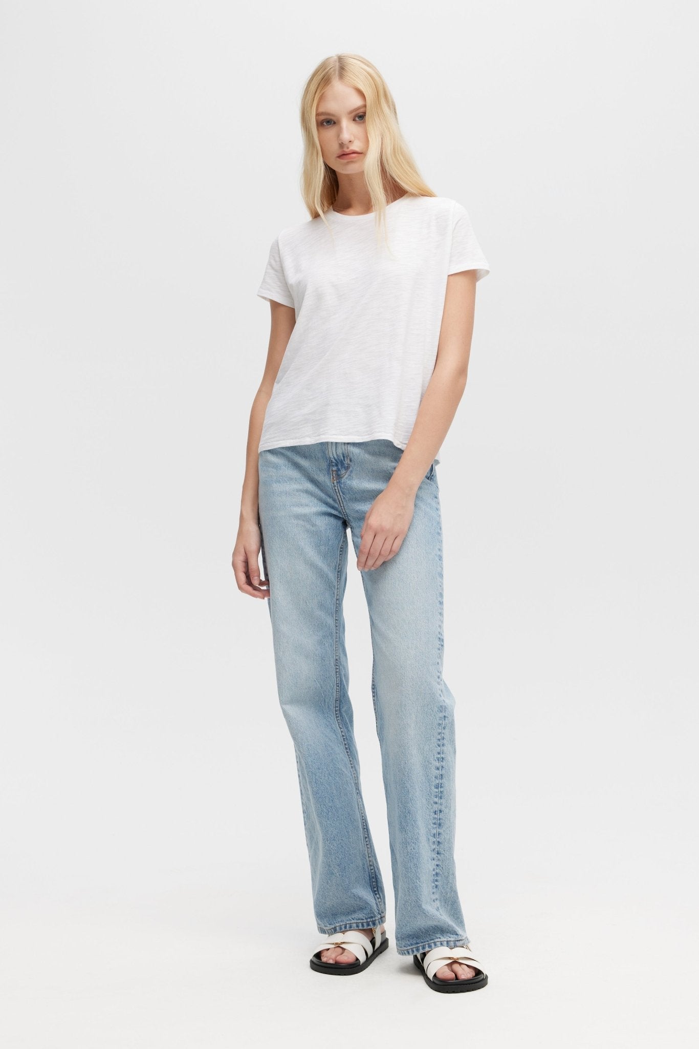 Woman wearing a white t-shirt and light blue jeans on a white background