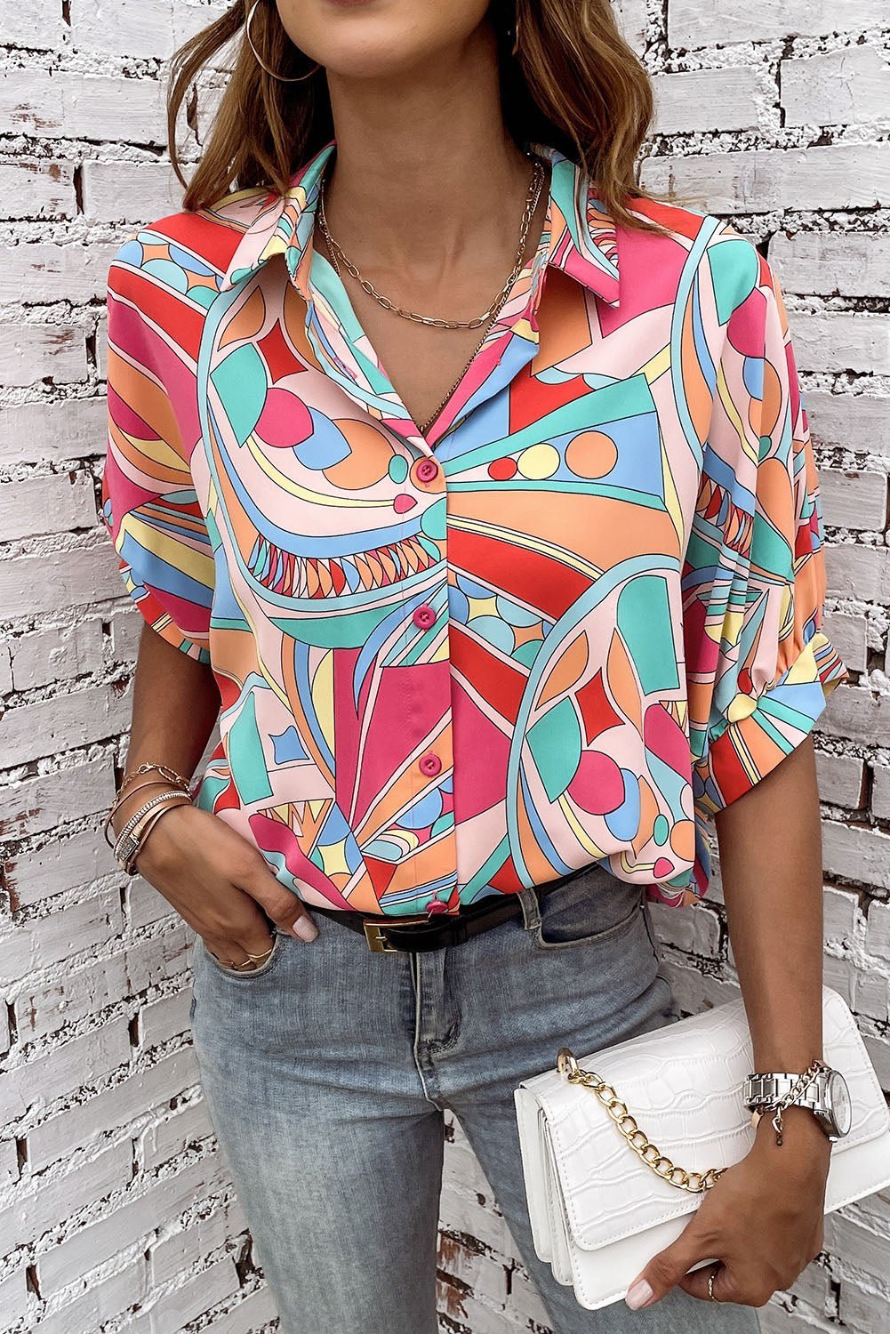 Person wearing a colorful patterned shirt with a white brick wall background