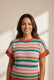 Woman wearing a colorful striped sweater against a neutral background