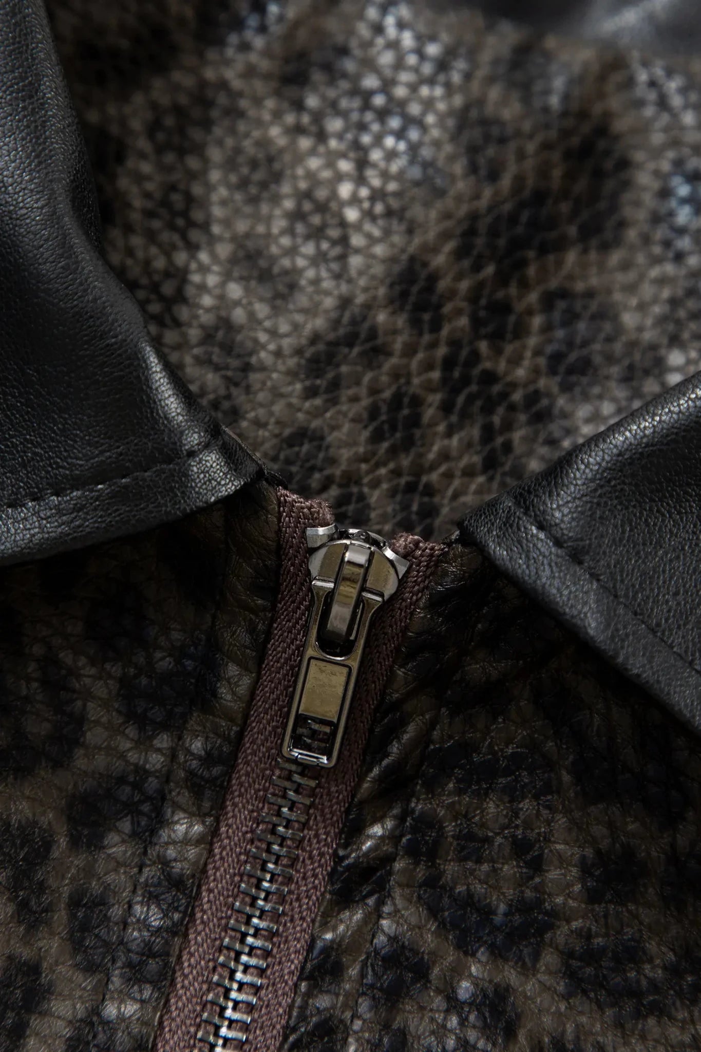 Close-up of leopard-print faux-leather collar with black trim and a silver metal zipper.