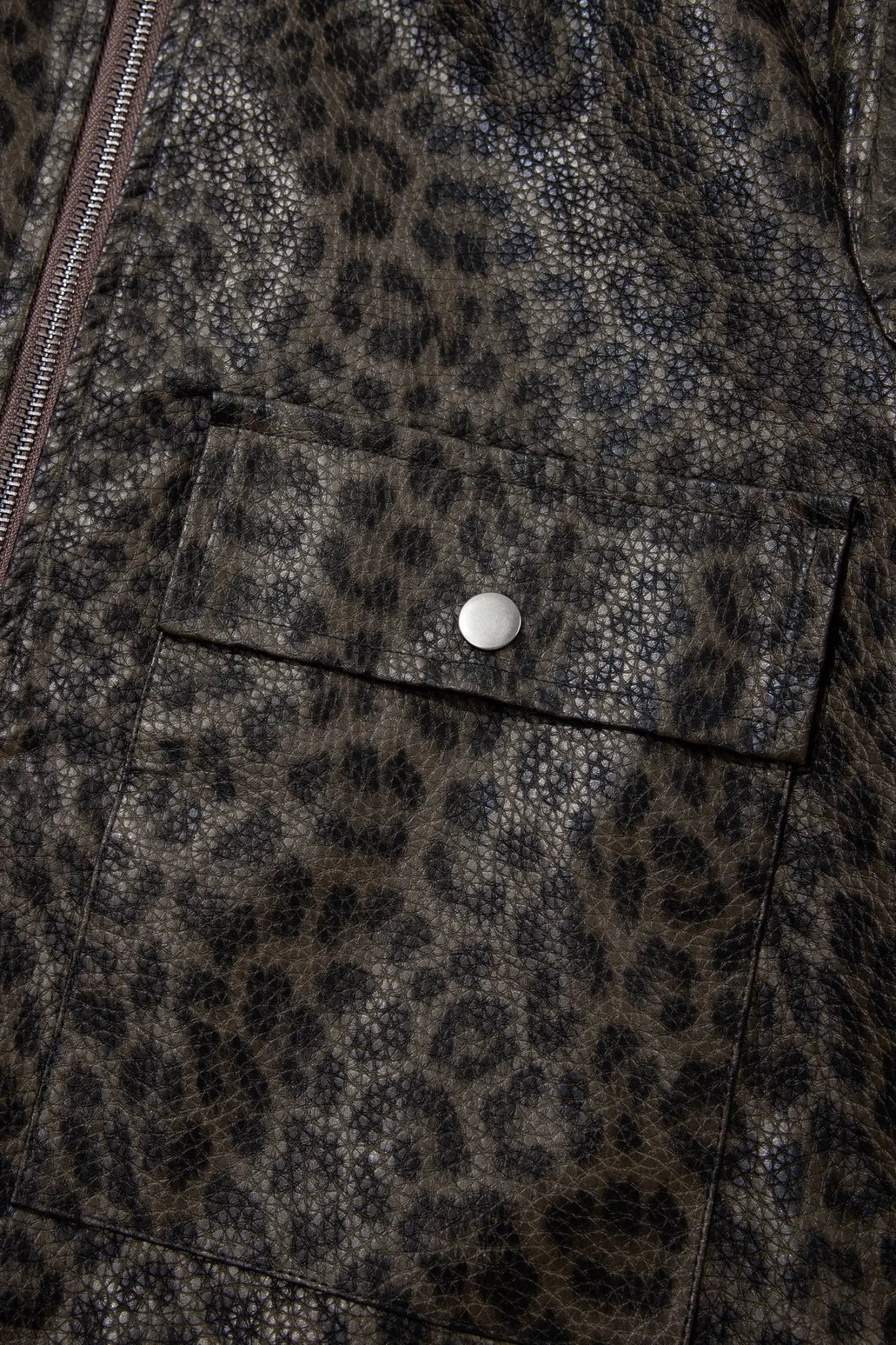 Close-up of brown and black leopard-print jacket with flap pocket, silver snap button, and side zipper.