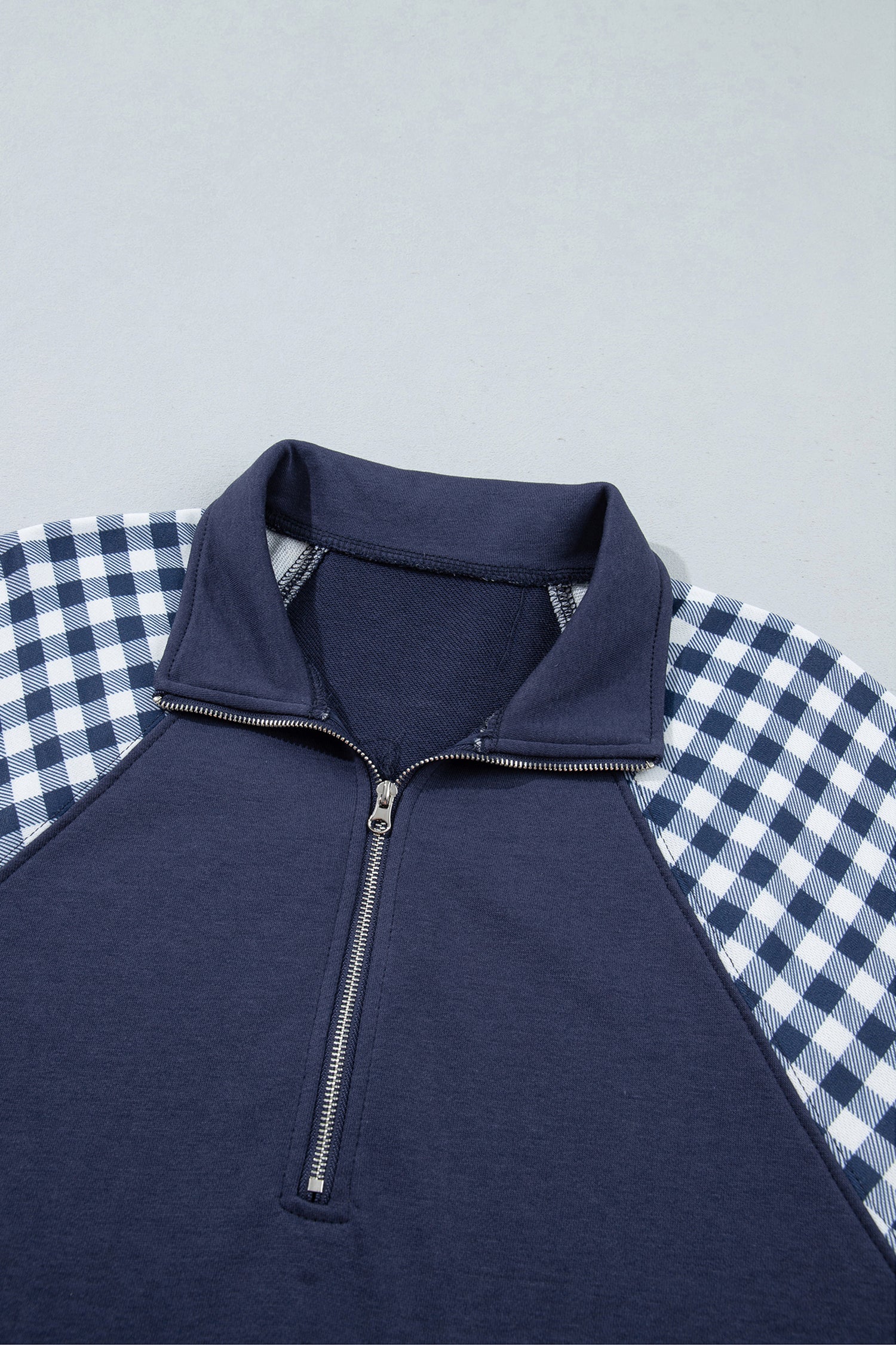 Navy blue quarter zip sweatshirt collar and gingham shoulders, close-up
