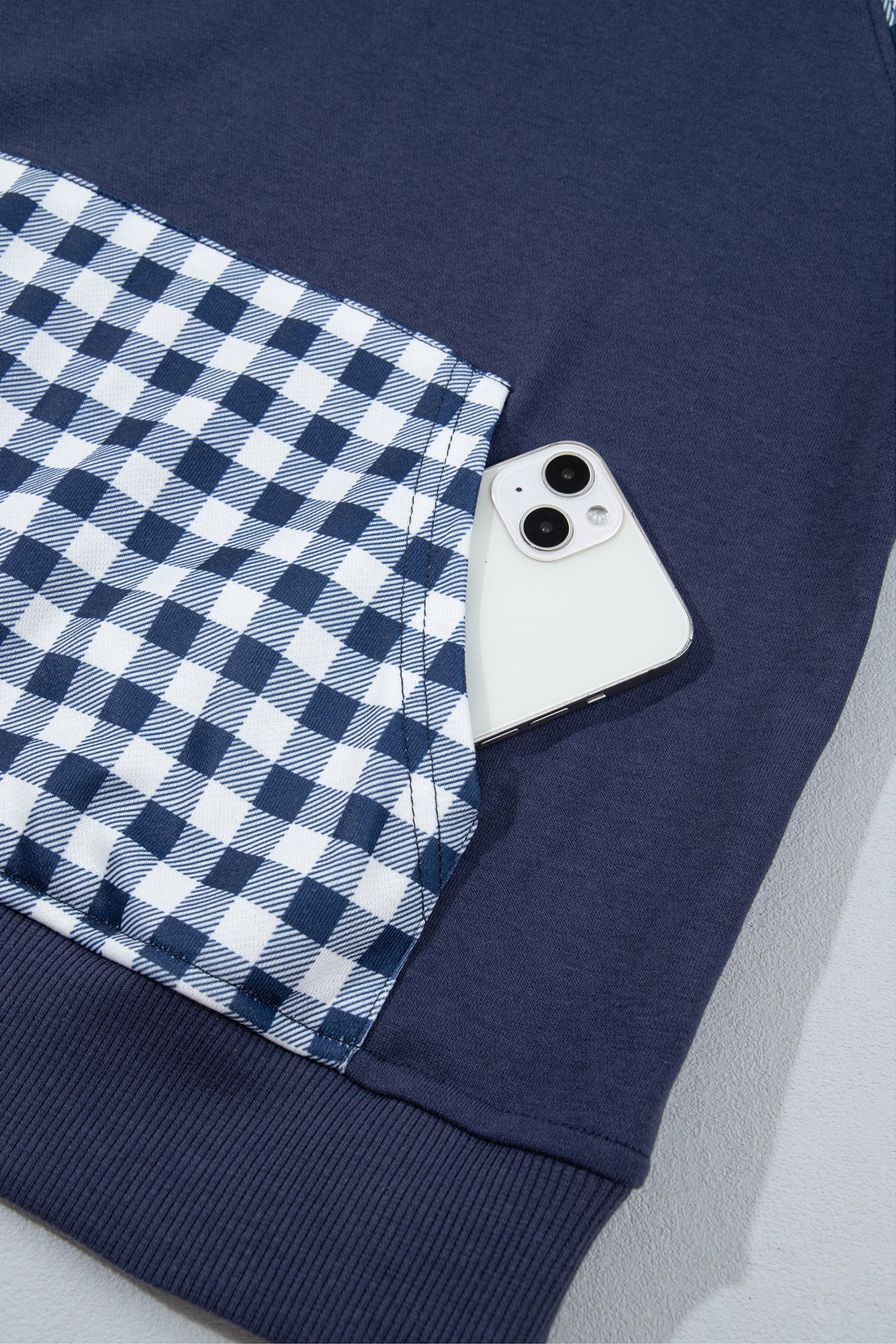 Navy blue sweatshirt gingham kangaroo pocket holding a phone