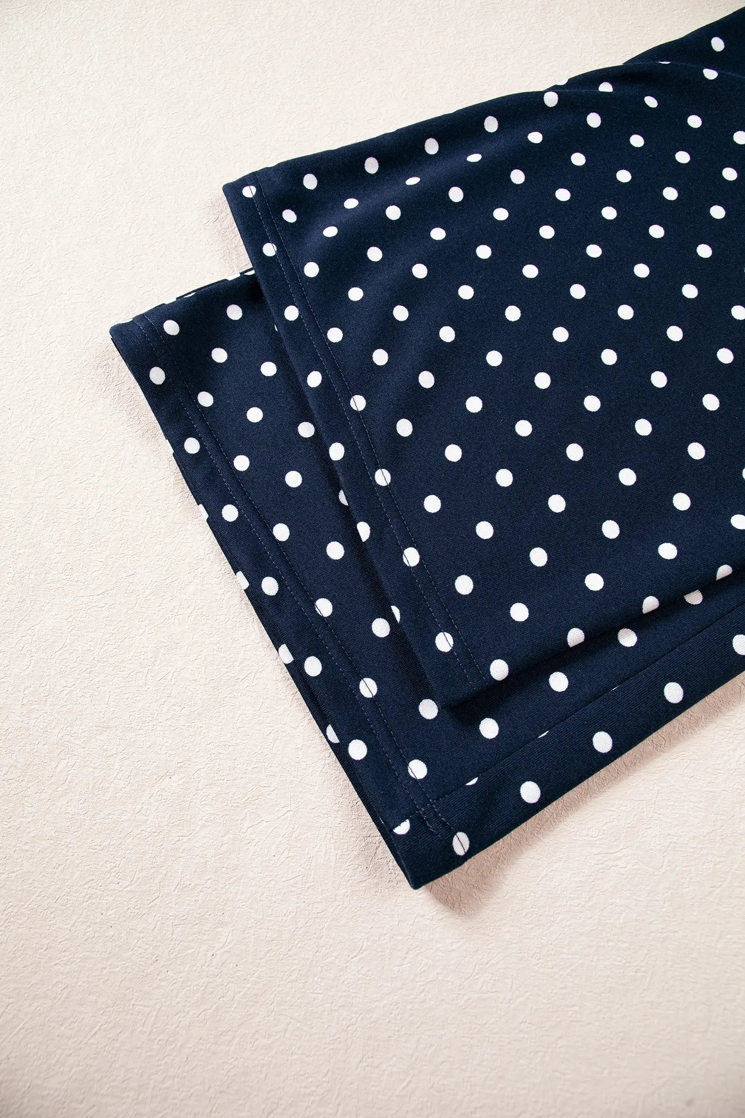 Wide leg hem of the navy polka dot pants laid flat