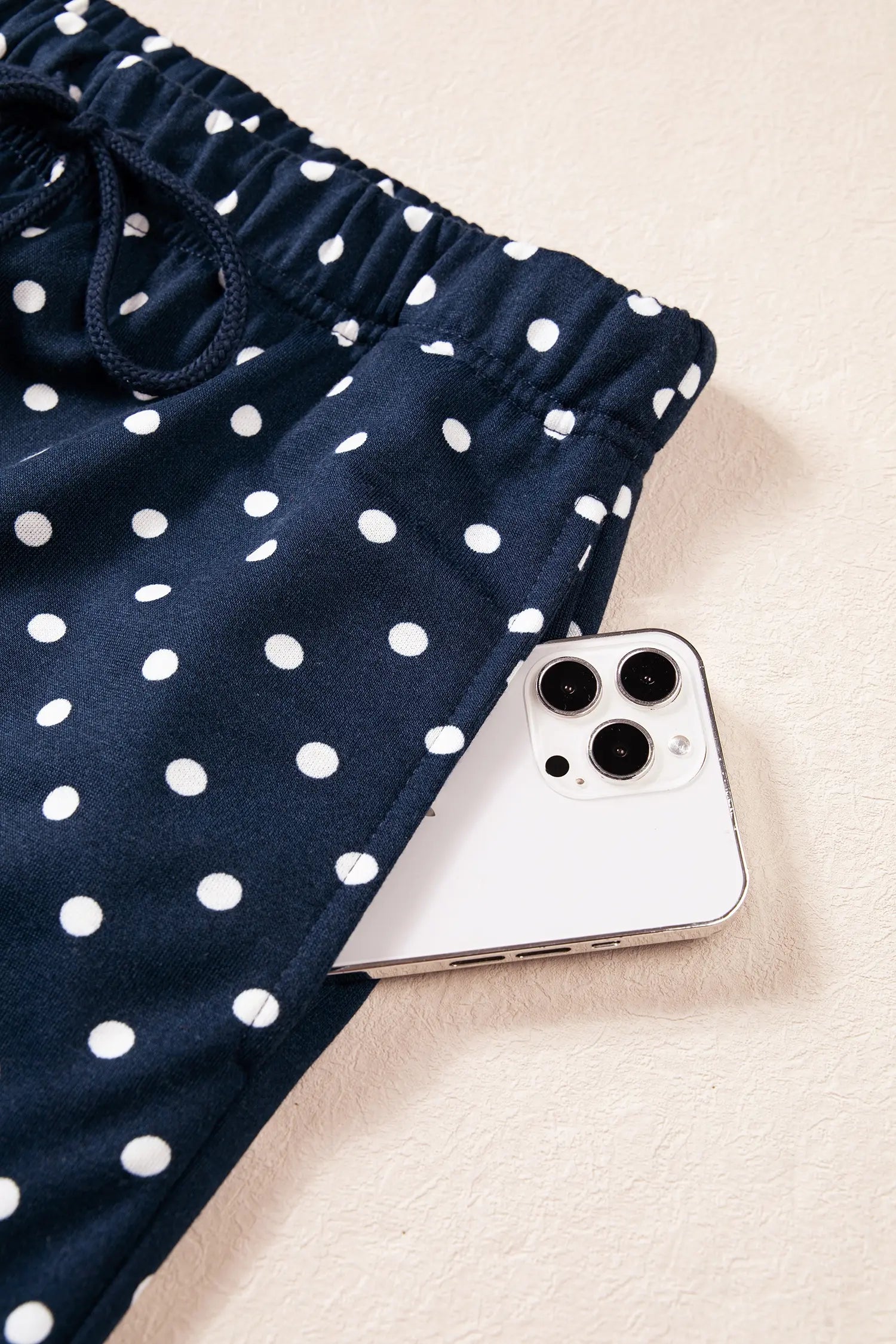 Navy polka dot drawstring pants with a phone in the side pocket