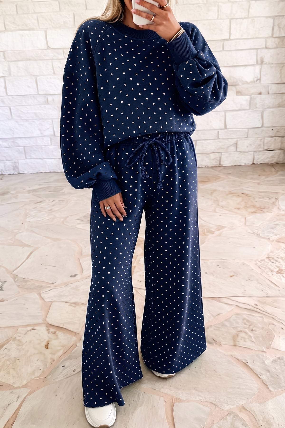 Woman wearing a navy polka dot raglan sleeve top and drawstring wide leg pant set