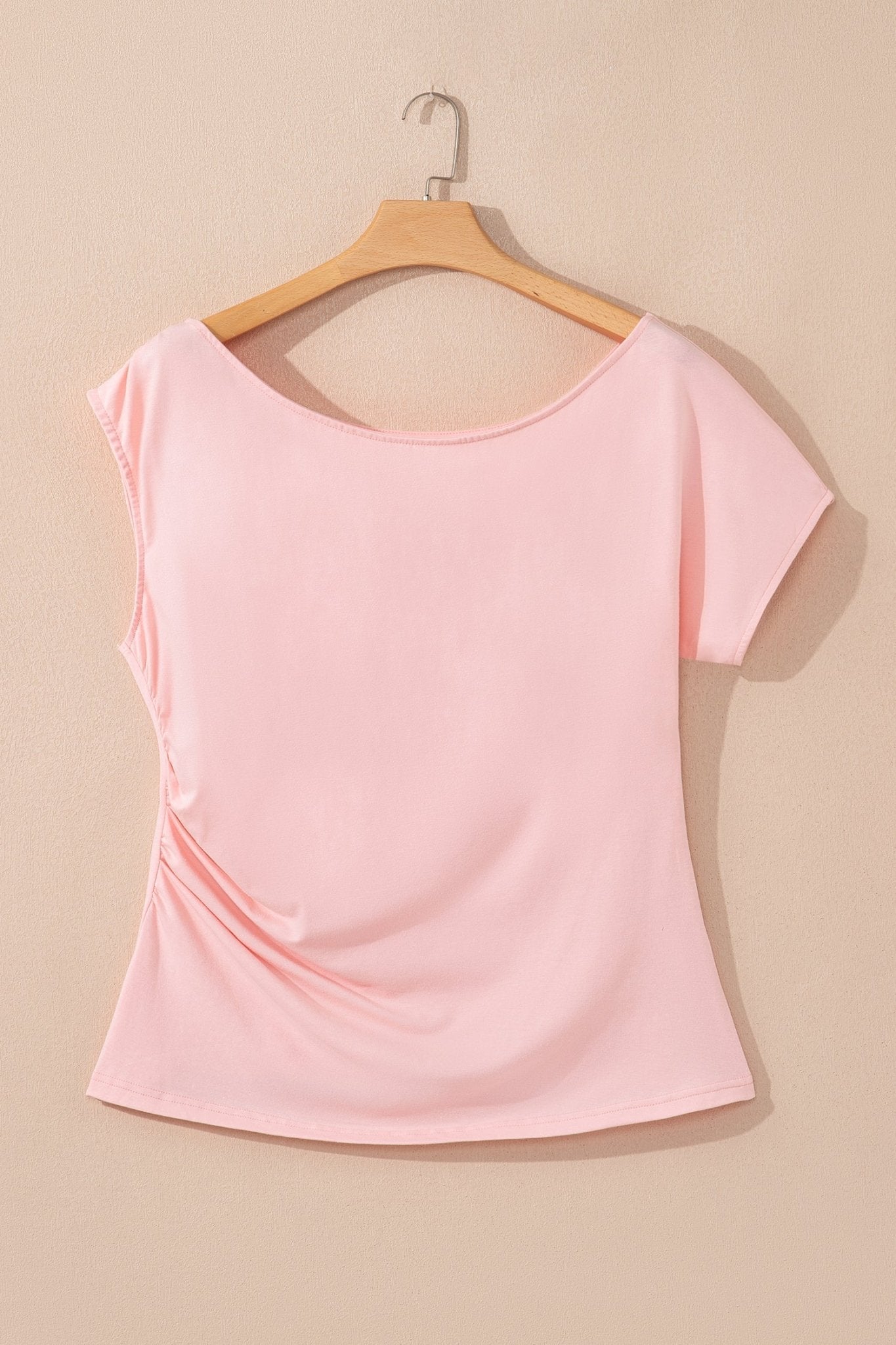 Pink top on a wooden hanger against a beige background