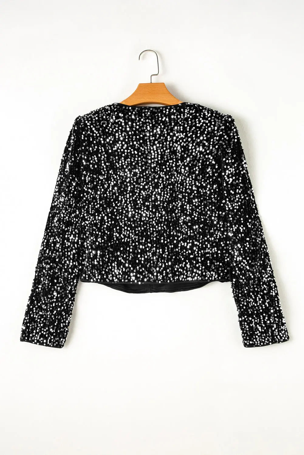 Black sequin top on a hanger against a white background