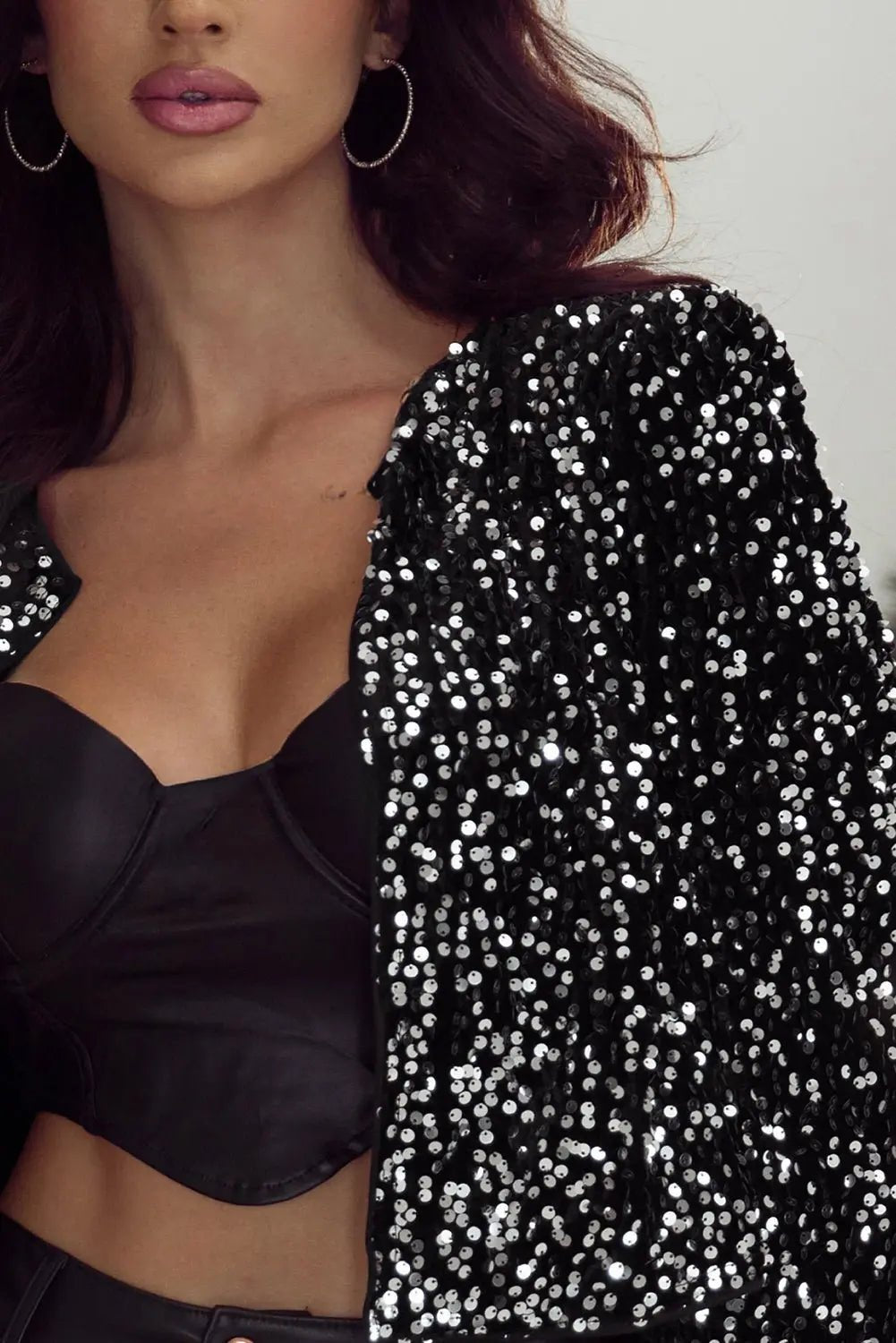 Woman wearing a black sequin jacket over a black top against a neutral background