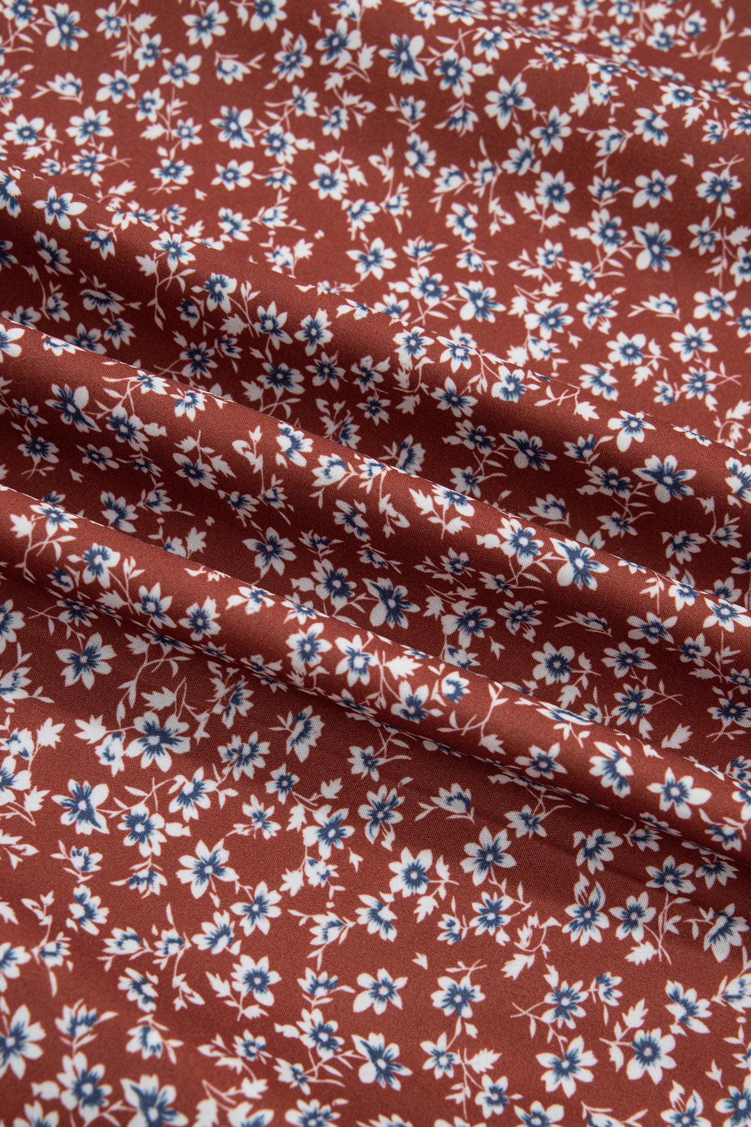 Close-up of rust ditsy floral print fabric in white and blue