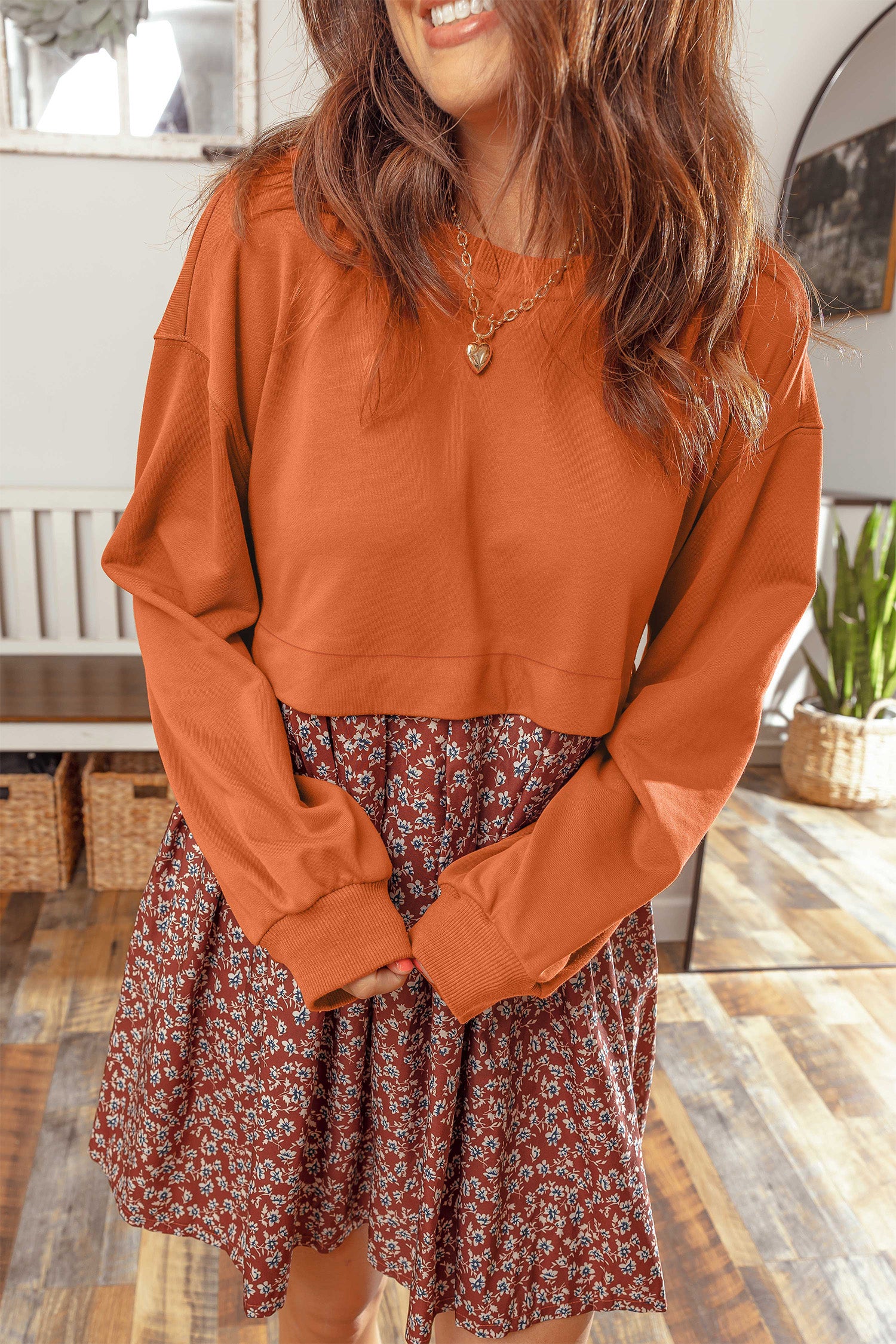 Woman in orange knit top and rust floral skirt 2-in-1 long sleeve mini dress, front view