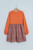 Orange and rust floral 2-in-1 long sleeve mini dress on a hanger, back view