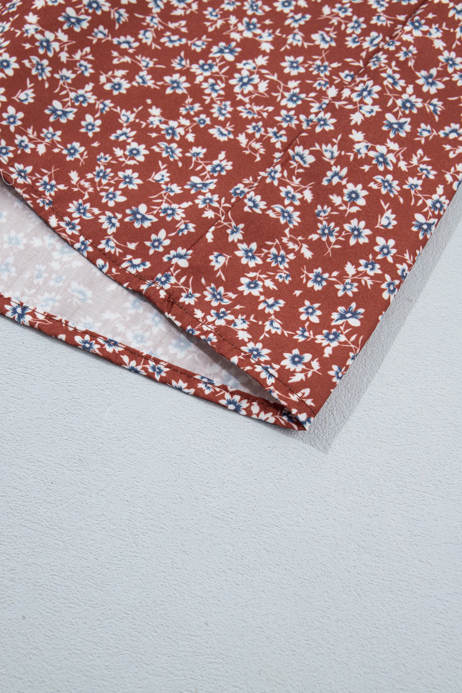 Hem detail of rust floral flared skirt with white and blue flowers