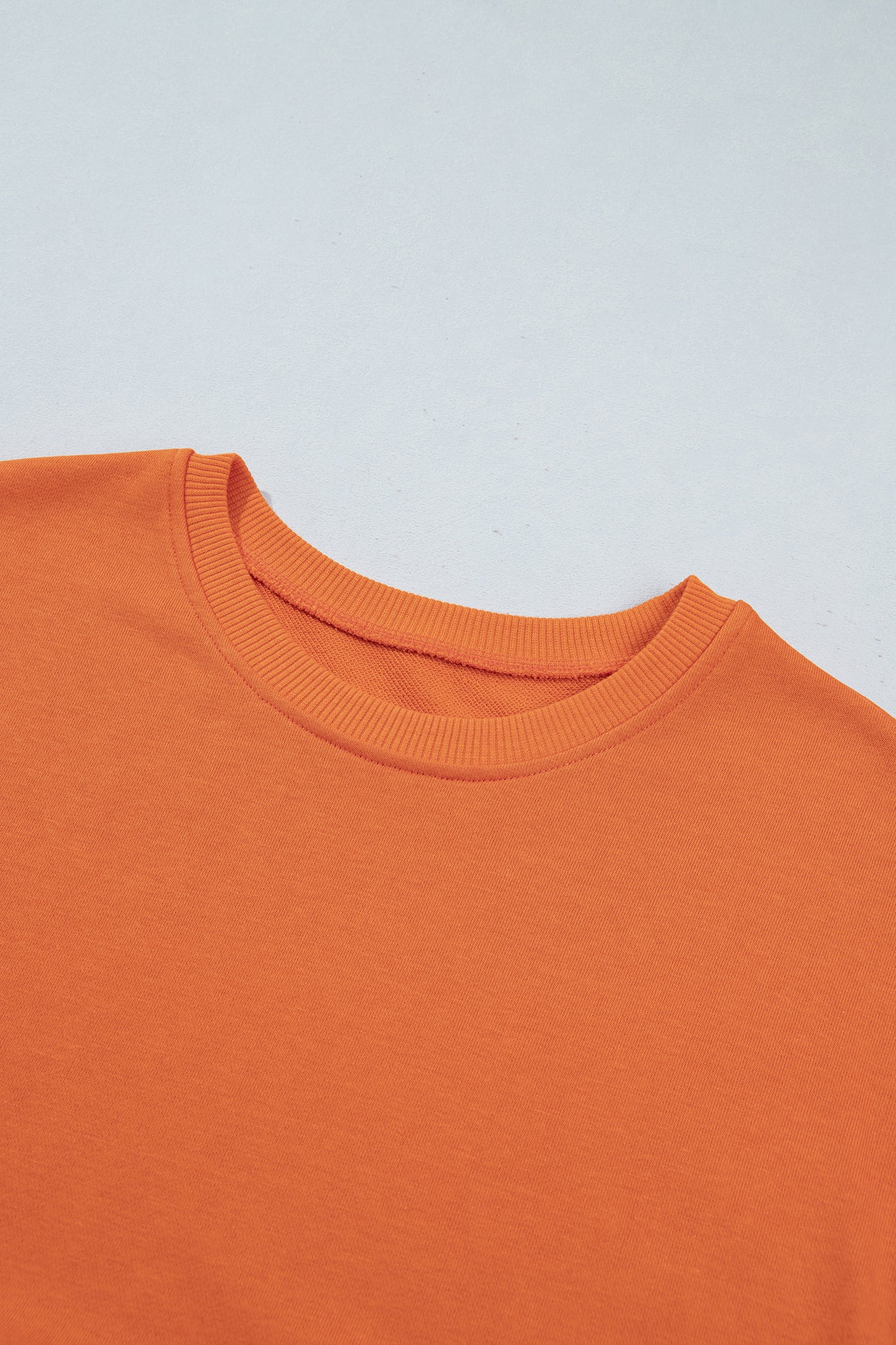 Close-up of ribbed round neckline on orange 2-in-1 mini dress
