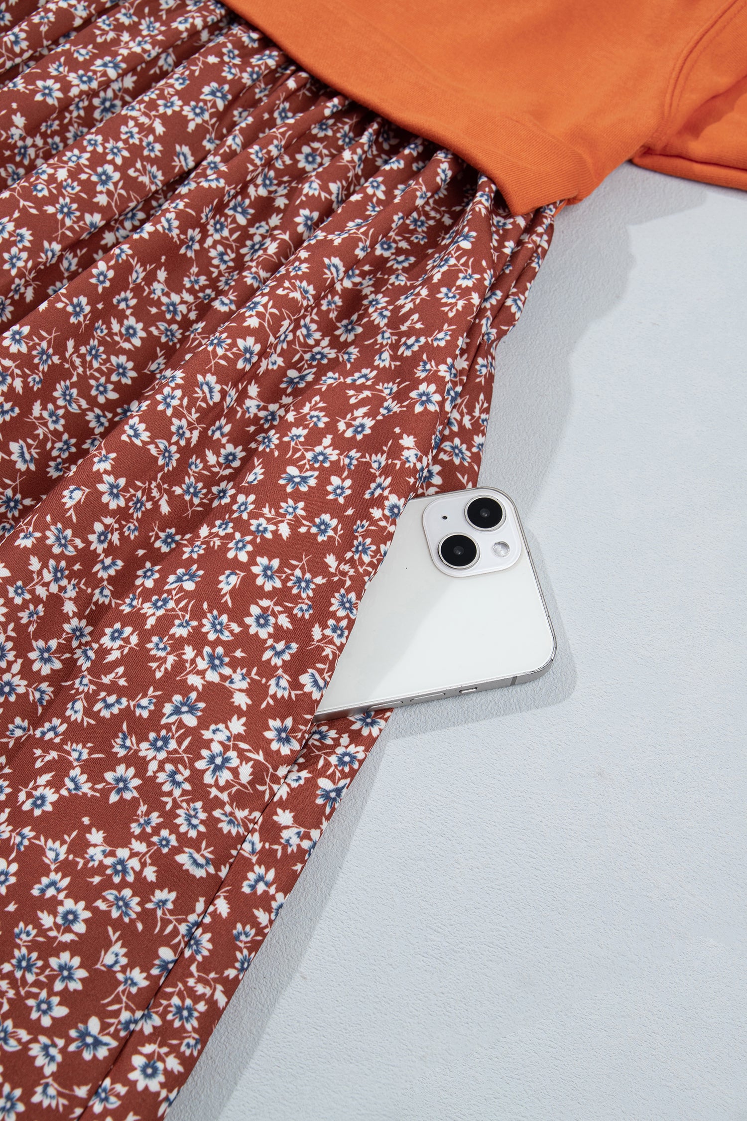 Side pocket holding a phone on rust floral skirt of orange 2-in-1 dress