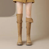 Tan knee-high boots worn with a mustard skirt on a neutral background
